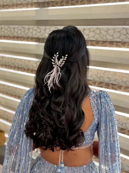 The full view of the feather and crystal half-up style. The accessory adds a touch of playful elegance to the soft waves.