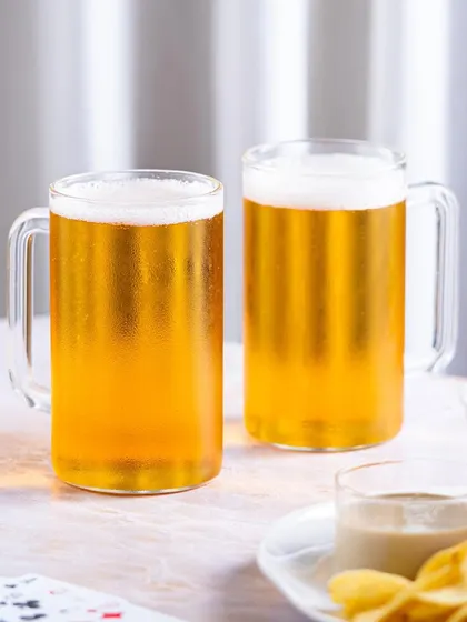 A simple and clean product shot of two beer mugs with snacks, against a neutral background. Versatile for any kind of marketing material.