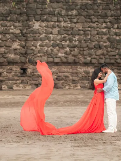 A tender moment on the beach. The flowing red trail of her gown creates a beautiful line and adds a touch of magic to this romantic pre-wedding photograph.