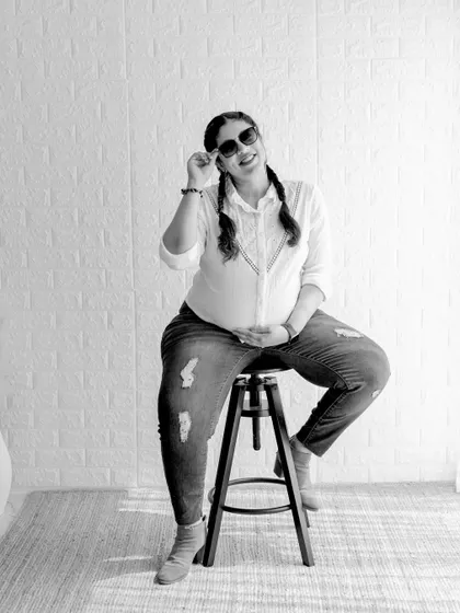 A fun and stylish casual portrait in black and white. The mom-to-be's playful pose with sunglasses and casual attire shows a different, more modern side of maternity photography.
