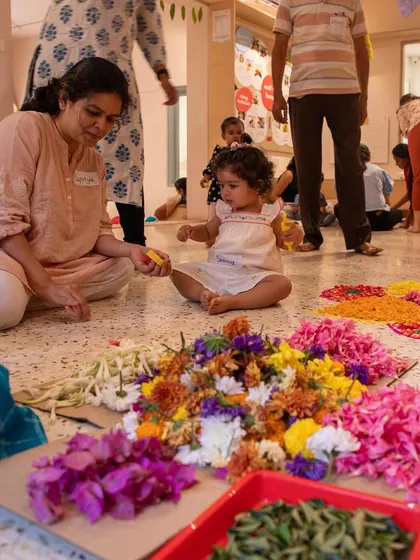 A toddler surrounded by a vibrant array of flower petals. This photo highlights our use of natural, safe materials for sensory exploration during our festive events.