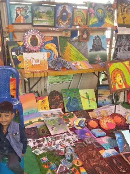 My son sitting proudly next to my art display at Chitra Santhe.