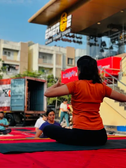 A member holds a seated twist pose, demonstrating focus and control with our studio in the background.