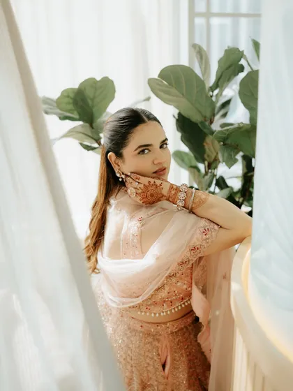 A beautiful portrait of the bride during her engagement ceremony, showcasing her intricate henna and elegant outfit. The soft, natural light adds a dreamy quality to the image.