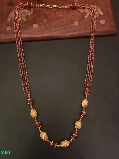 A multi-strand beaded necklace in a rich maroon color. The necklace is made from 92.5 silver with gold plating and features beautiful leaf-shaped golden beads.