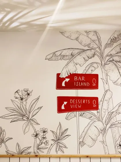 Fun, directional signs painted as part of the larger tropical mural, guiding guests to the 'Bar Island' and 'Desserts View'.