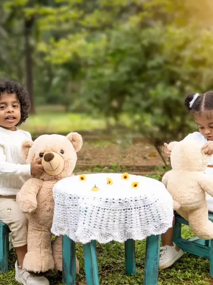 The twins playing with their teddy bears at a small table. Outdoor shoots allow for natural and spontaneous play.