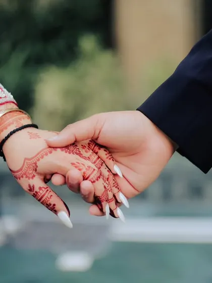 A symbolic shot of the couple holding hands, showcasing the bride's beautiful henna. This simple gesture represents their promise and connection.