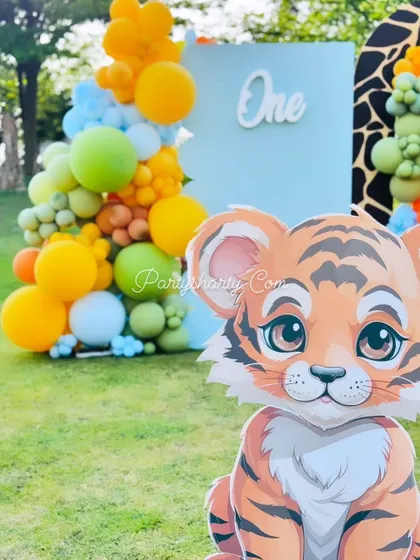 A close-up of a cute tiger cub prop for an outdoor jungle party, set against a backdrop of colorful balloons, perfect for a 'Wild One' celebration.