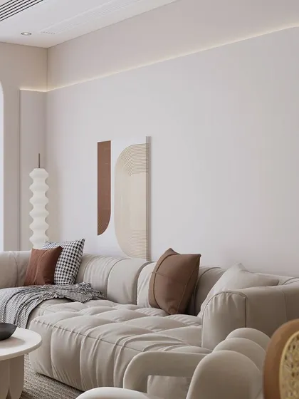 This living room design uses architectural arches and soft, integrated lighting to create a gentle, flowing aesthetic. The tufted sofa in a neutral fabric is paired with brown and houndstooth pillows, adding warmth and a classic touch to the contemporary setting.