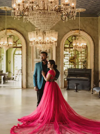 For a touch of royal elegance, this magenta trail gown is a favorite for pre-wedding shoots. Its long, flowing train spreads out beautifully against the grand backdrop of this palace hall, creating a truly cinematic and romantic photograph.