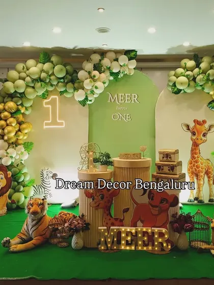 A cute and friendly animal theme for Meer's first birthday. The setup features a soft green backdrop, plush animal toys, and a balloon arch in green and gold.