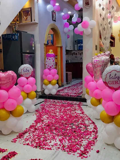 An indoor view of the 'Welcome Baby' party, with a rose petal walkway leading into the house, lined with balloon pillars.