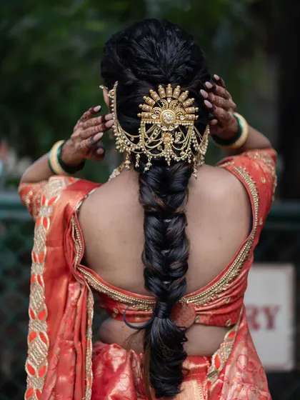 The back view showcases the traditional braided hairstyle adorned with a stunning gold hair accessory, completing the bridal look.