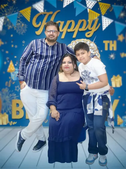 A family poses against a blue and gold 'Happy Birthday' backdrop. We are experts at taking great photos in front of party decorations and photo booths.