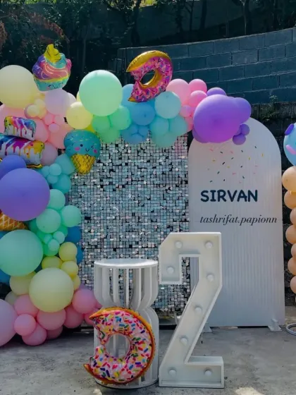 A sweet Candy Land theme with ice cream and donut shaped foil balloons, a pastel balloon arch, and a "2" marquee number.