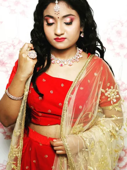 A close-up of the red lehenga set, showing the red velvet blouse and the delicate embroidery on the sheer gold dupatta.