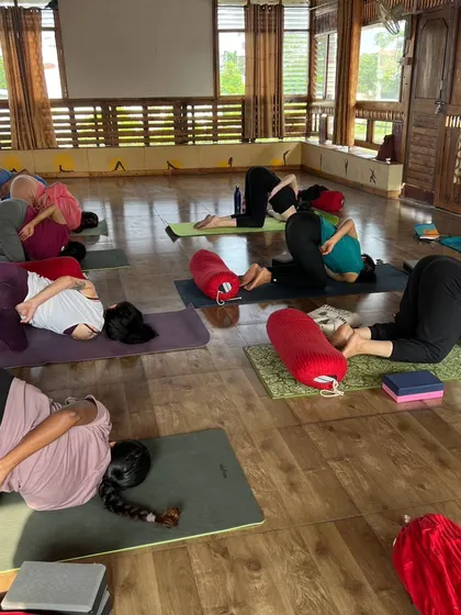 A Yin class in session, with students using bolsters to support them in a gentle twist, embracing stillness and surrender.