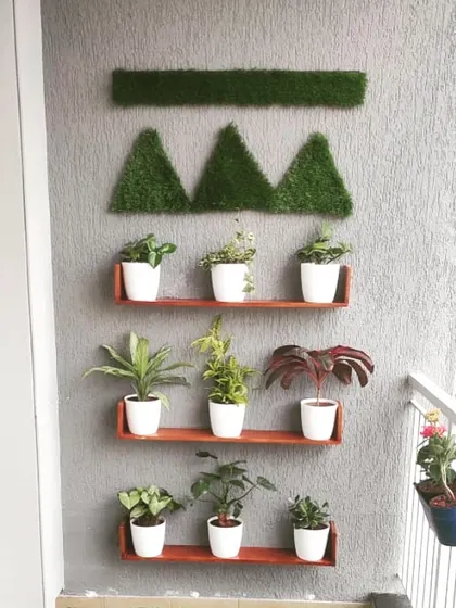 We love creating living wall art. This setup uses simple wooden shelves and geometric turf patterns to display a collection of small plants in white pots, turning a plain balcony wall into a stylish feature.