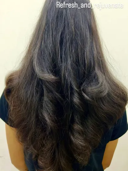 A back view of the layered haircut, highlighting the soft waves and voluminous finish.
