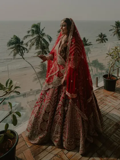 A full-length bridal portrait on a balcony overlooking the ocean in Goa.