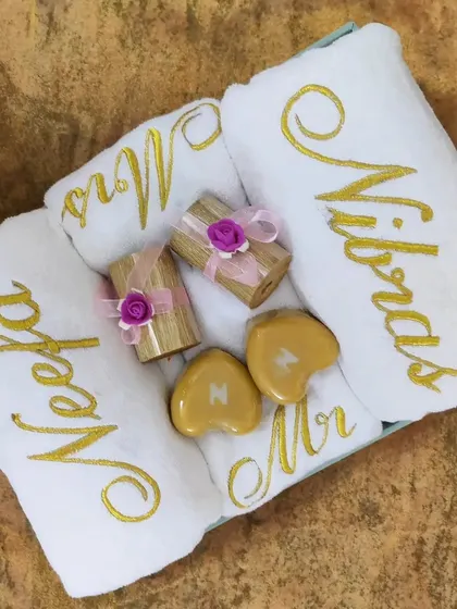 This hamper has it all: bath towels with the couple's names, hand towels embroidered with 'Mr' and 'Mrs', golden heart-shaped soaps with their initials, and two luxury candles. It’s a complete gift set.