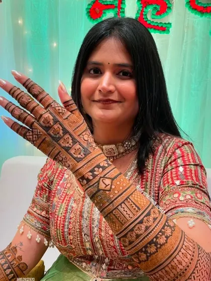 A close-up of the bride's hand, highlighting the detailed jaali work and the initial "Y" incorporated into the design.