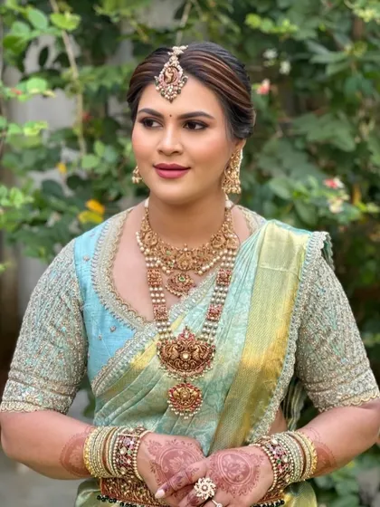 A bride in a pastel blue Kanchipuram saree. Her custom blouse is heavily embroidered with thread and beadwork, matching the grandeur of her traditional temple jewelry.