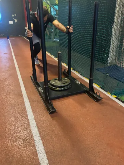 A client pushes the sled, fully engaged in this demanding conditioning exercise.