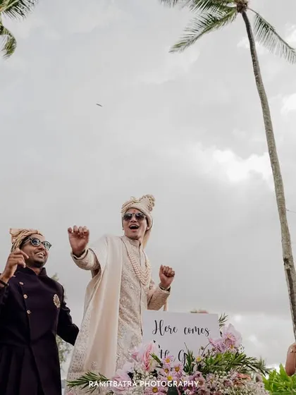 The groom's energetic Baraat makes its way through the palm trees at a beach wedding in Thailand.