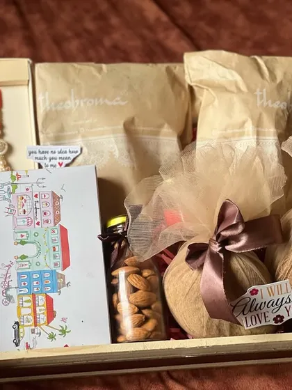 A Rakhi hamper with a rustic and traditional feel. It includes rakhis, a greeting card, almonds, and other items arranged on a simple wooden tray.