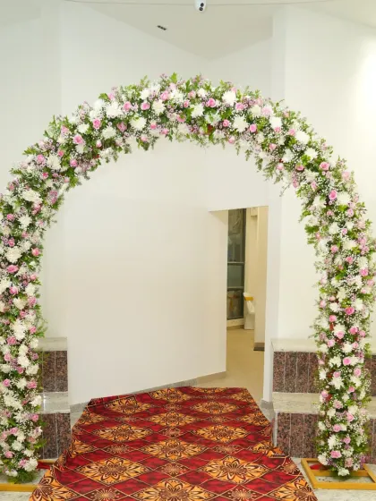A full floral arch at the entrance of a home for a housewarming, creating a grand welcome for guests.
