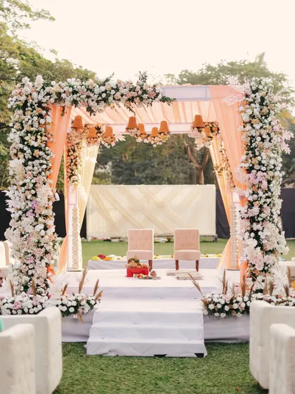 The full view of a dreamy outdoor mandap in Alibaug, adorned with beautiful pastel flowers and elegant drapery, perfect for a fairytale wedding.
