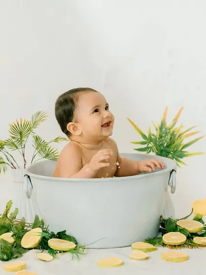 Looking up with a happy grin, this baby is loving his lemon bath. The simple white background makes the colors pop.