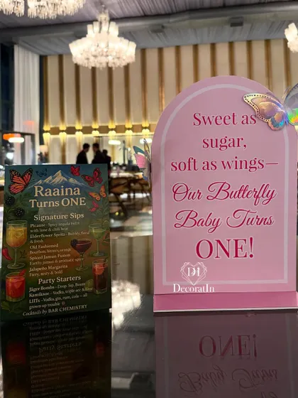 Custom-designed table stationery, including a "Signature Sips" bar menu and a sweet sign celebrating the "Butterfly Baby."