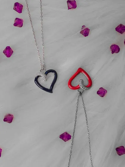 A simple and clean product shot of two heart-shaped necklaces. The fluffy white background and scattered purple gems create a playful and romantic feel, perfect for marketing these accessories.