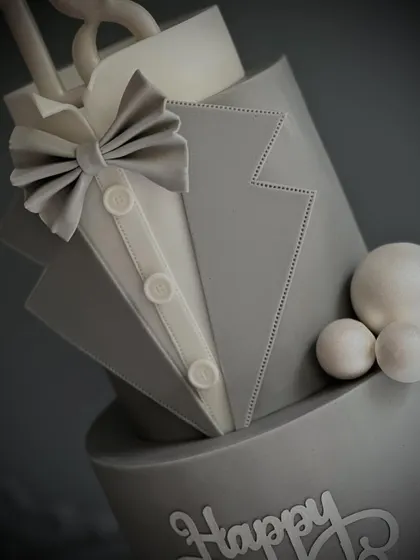 A close-up view of the sharp, clean lines on this gentleman-themed cake. We teach you how to create realistic fabric textures and details like the shirt, lapels, and bow tie using fondant.
