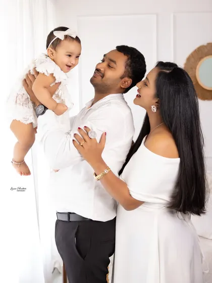 A father lifts his laughing baby girl towards the light. This image showcases our bright and airy style, capturing pure joy and connection.
