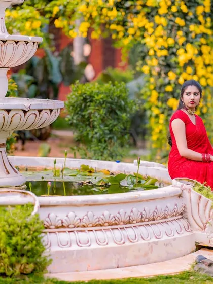 An elegant portrait by a classic white fountain. The bride's red dress looks stunning against the lush greenery and the white architecture.