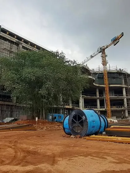 The Inorbit Vizag site during construction, showing the scale of the development with multiple cranes at work. The design manages the site's natural gradients through stepped terraces and internal courtyards.