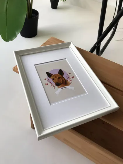 Another view of the framed Chiku portrait, showing how it looks as a finished piece on a wooden surface in my studio.