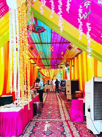 Another view of a colorful tent decoration for a housewarming. The ceiling is filled with bright drapes, and I've included hanging floral strings and traditional decor to enhance the festive look.