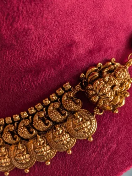 A macro shot of the Kaasu necklace, focusing on the craftsmanship of the individual coins and the Lakshmi motif at the clasp.