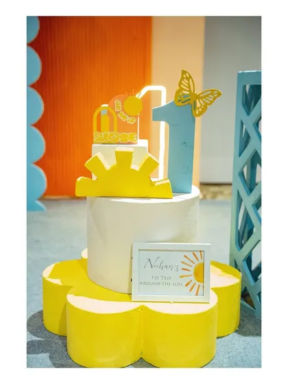 A detailed shot of the sunshine-themed cake topper and a personalized sign for Neehan's 'First Trip Around the Sun'.