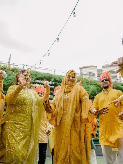 The ladies of the family dancing together, dressed in beautiful shades of yellow, celebrating the upcoming wedding with joy.