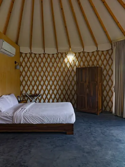 The spacious and airy interior of our yurt-style cottage, with a comfortable bed and natural-themed decor.