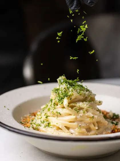 A final sprinkle of fresh parsley over my Vodka Pasta. This simple garnish adds a touch of freshness and color, completing the dish.