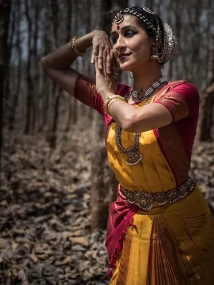 A close-up photograph that captures the detail of the costume and the emotion in the expression. The forest backdrop adds a sense of timelessness.