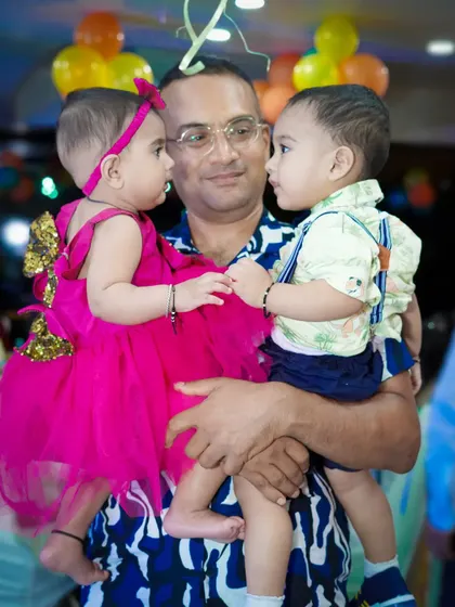 A father holds two young children, who are looking at each other. We capture these charming and spontaneous interactions between family members.