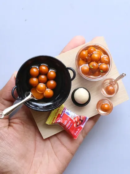 A beautiful miniature of gulab jamun being prepared in a tiny kadai, a sweet and delightful scene.